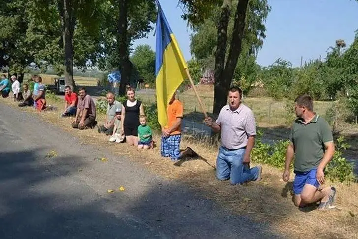 A Ukrainian on his knees with a flag